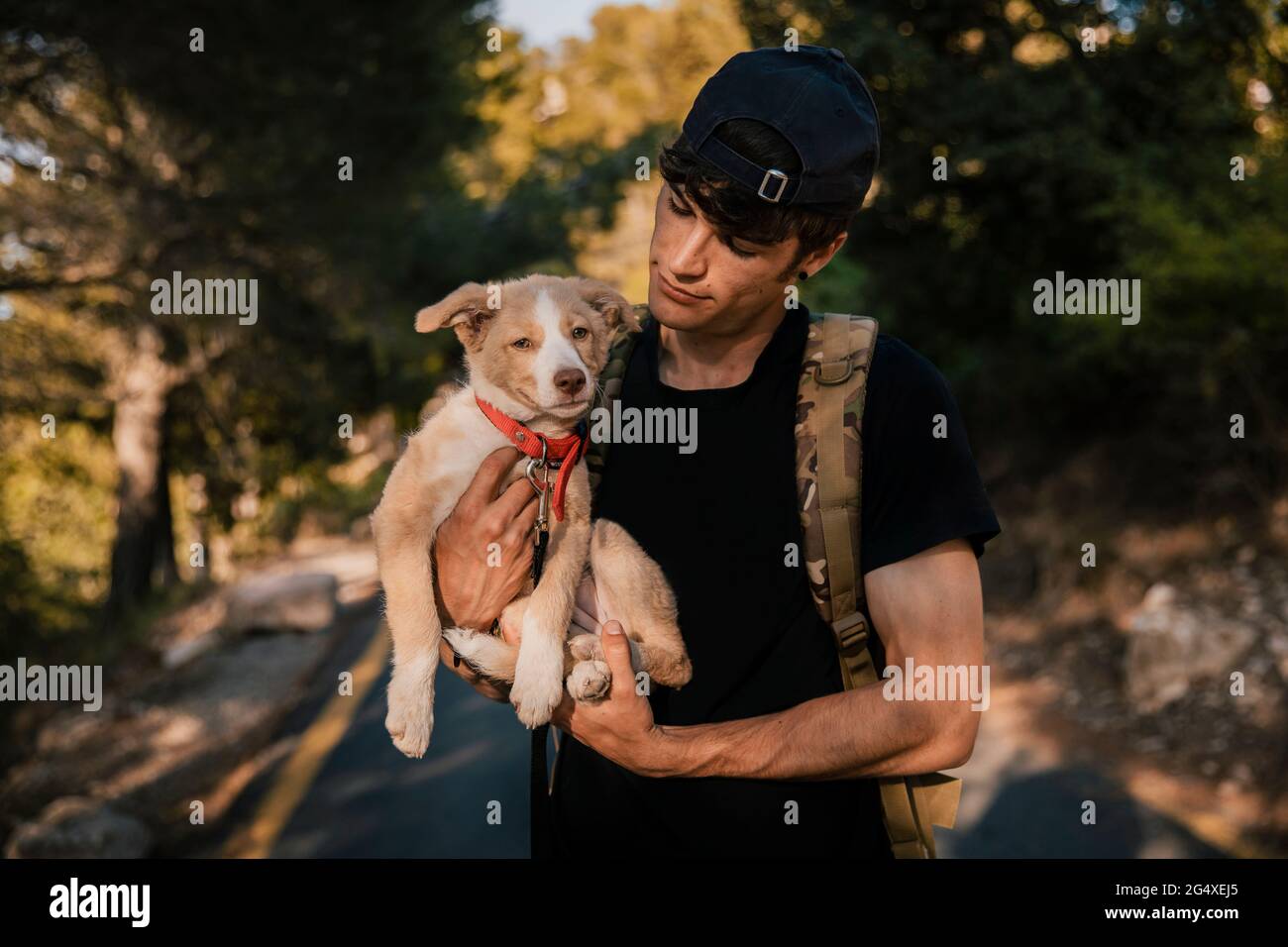 Giovane escursionista maschile in piedi con zaino e animale domestico in foresta Foto Stock