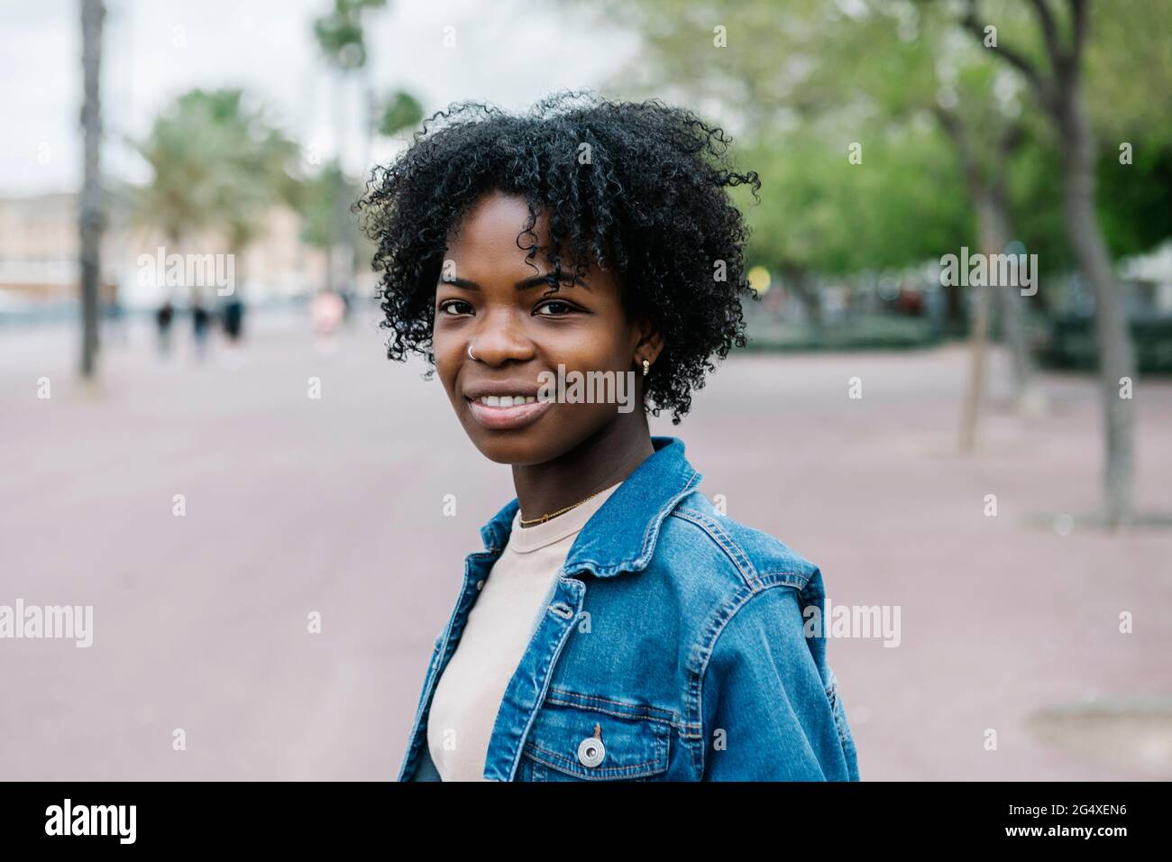 Giovane donna sorridente con capelli afro in città Foto Stock
