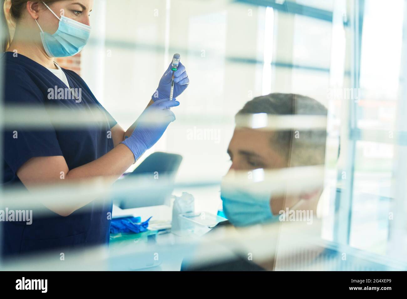 Operatrice di prima linea femminile che prepara la dose di vaccino COVID-19 per il paziente in clinica Foto Stock