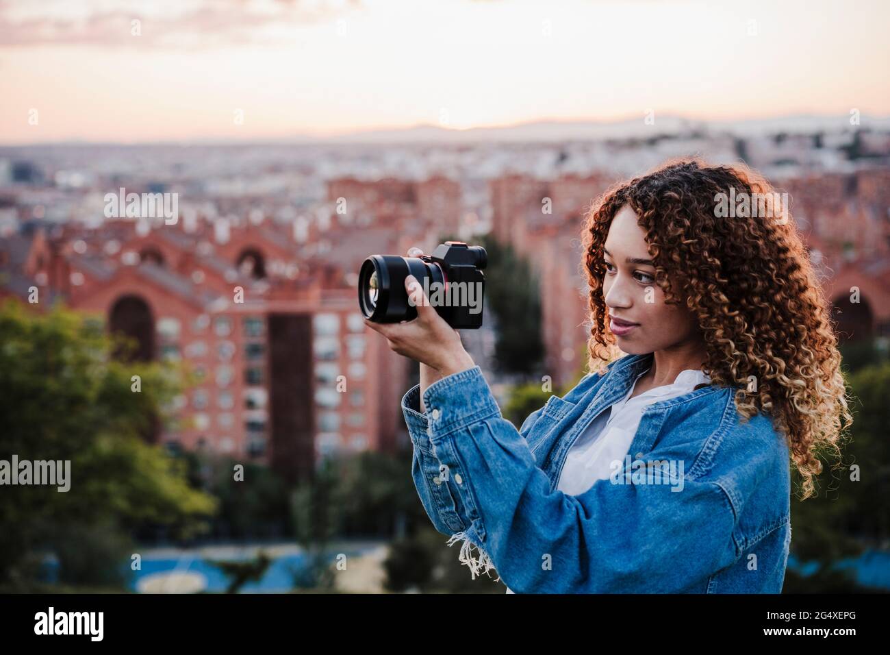 Giovane donna che fotografa attraverso la macchina fotografica per città Foto Stock