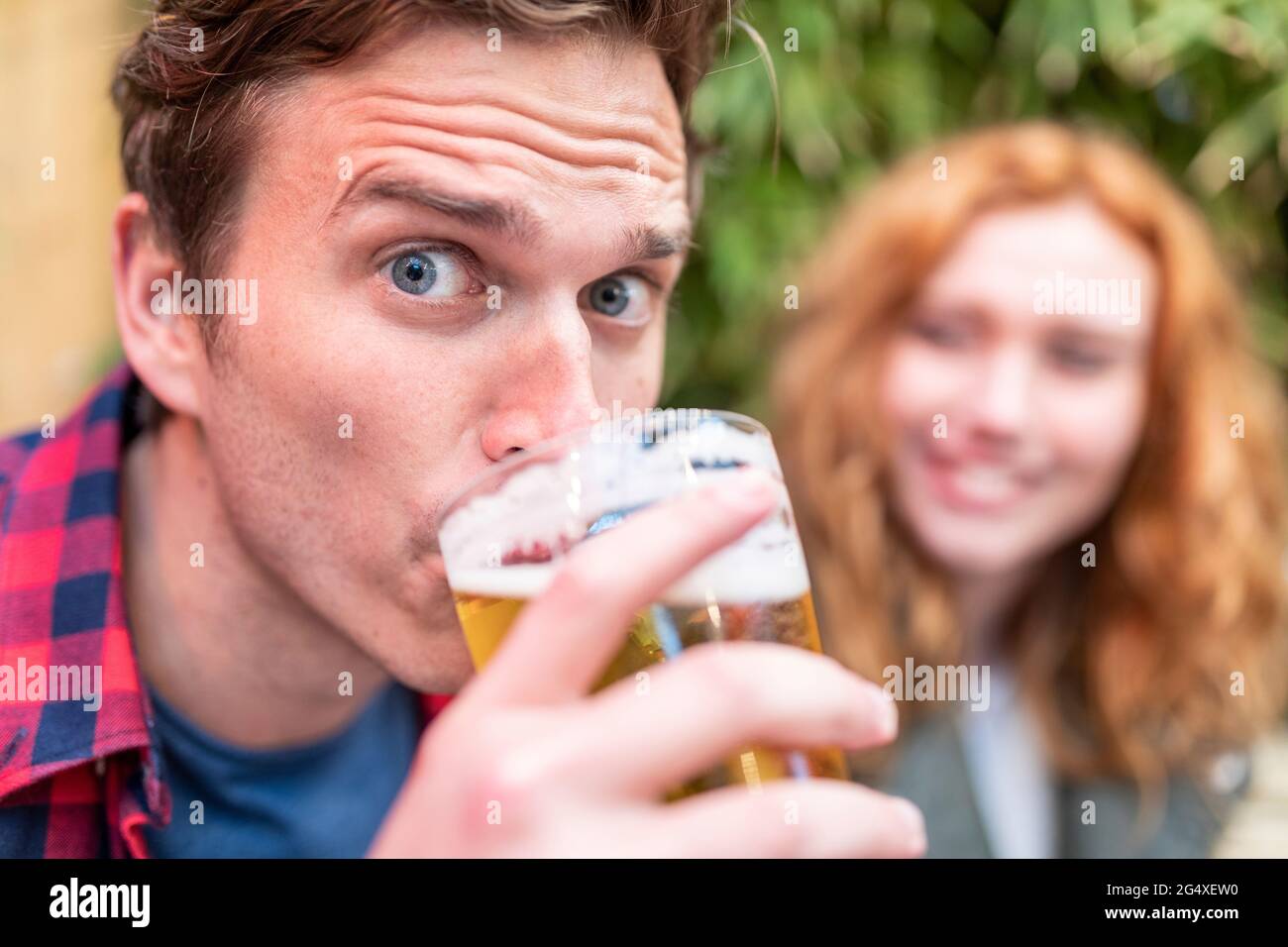 Uomo con sopracciglia rialzate che beve birra al pub Foto Stock
