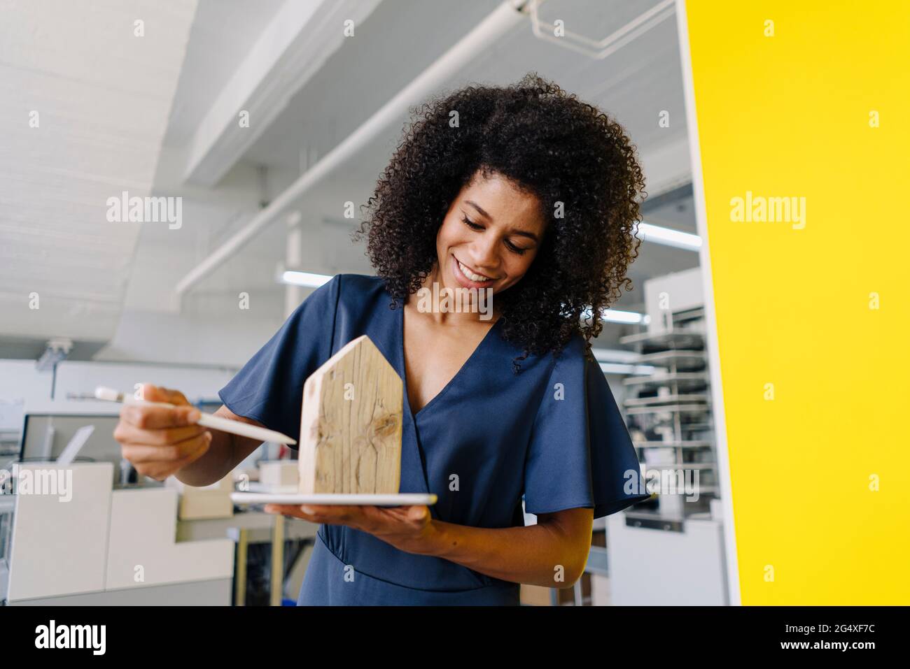 Sorridente agente immobiliare femminile che esamina il modello di casa in agenzia Foto Stock
