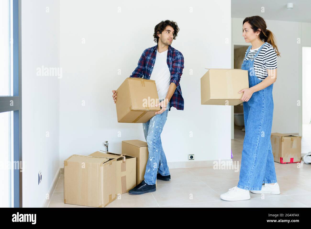 Giovane uomo e donna che porta scatole di cartone in una nuova casa Foto Stock