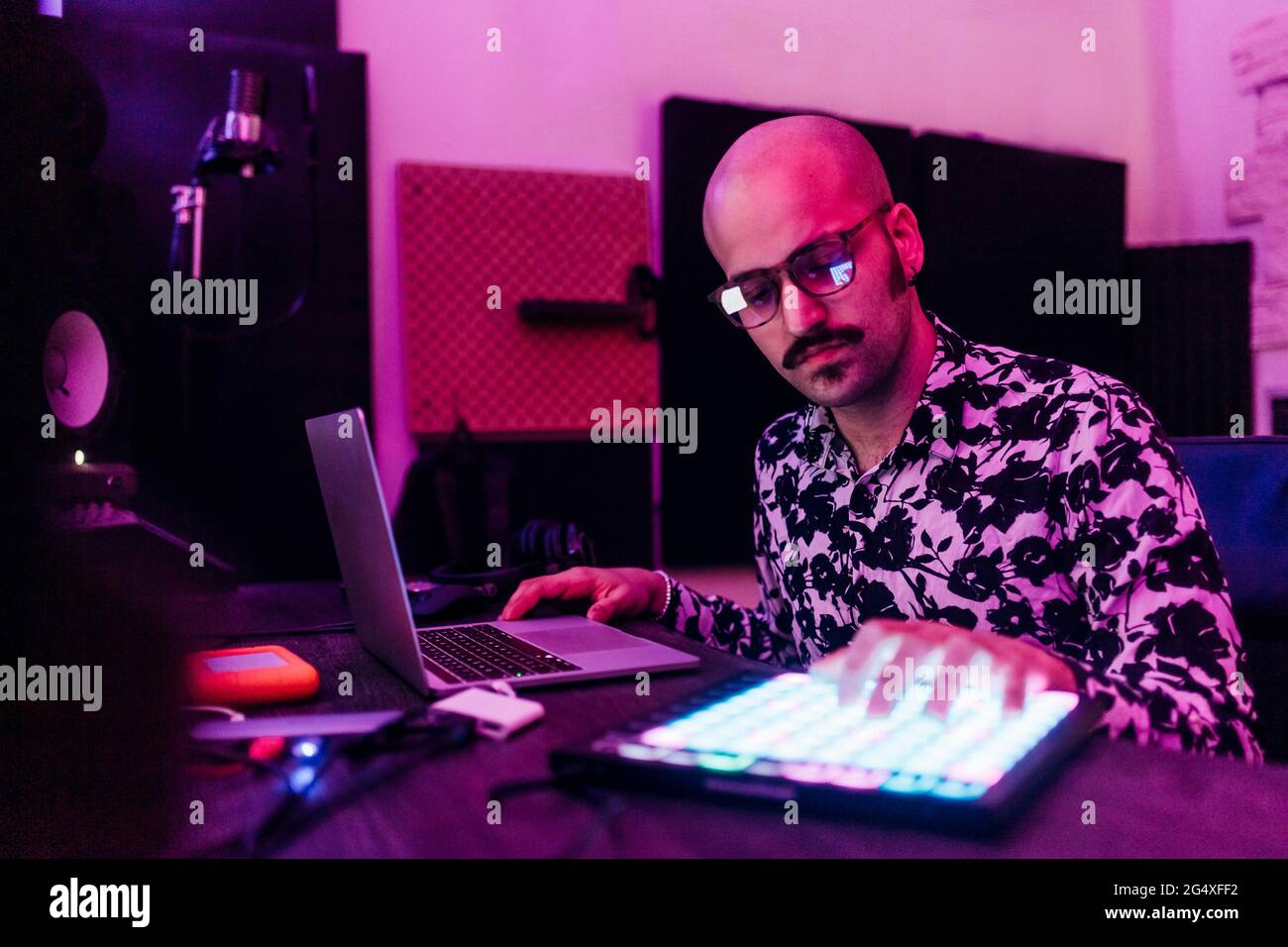 Compositore maschile che indossa occhiali che toccano il tablet digitale mentre componi musica in studio Foto Stock