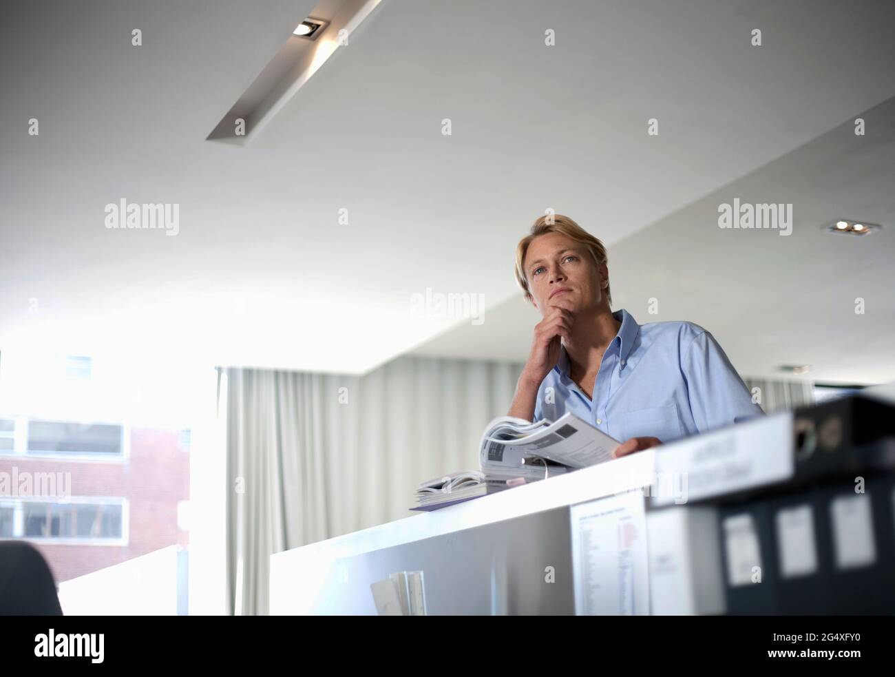 Professionista maschile premuroso che guarda via mentre si fa la documentazione in ufficio Foto Stock