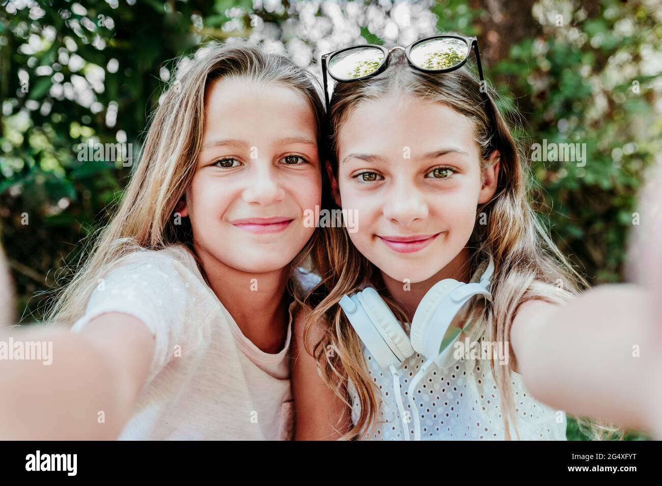 Sorridenti ragazze che prendono selfie in giardino Foto Stock
