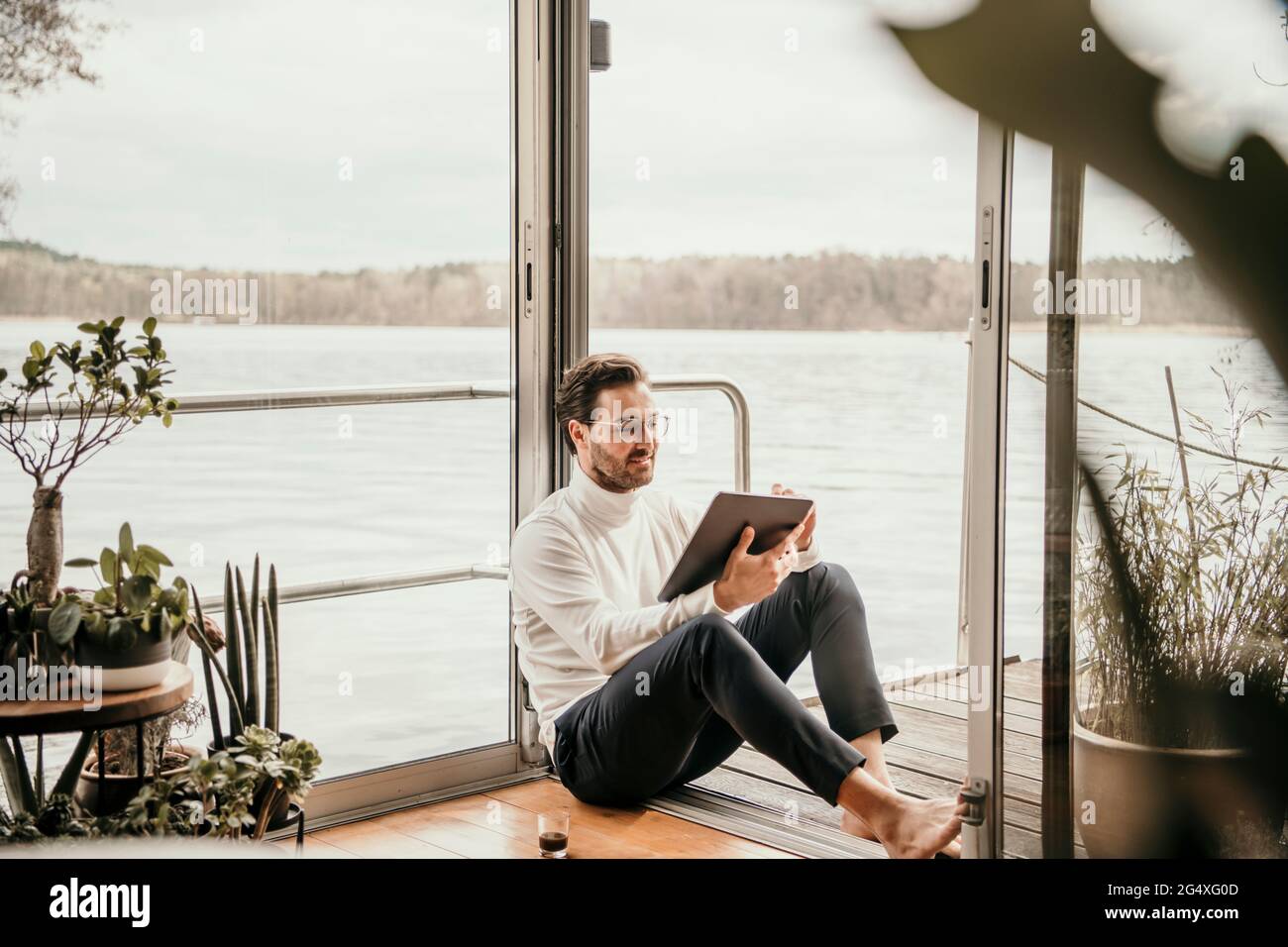 Lavoratore freelance maschile che utilizza un tablet digitale presso la casa galleggiante Foto Stock