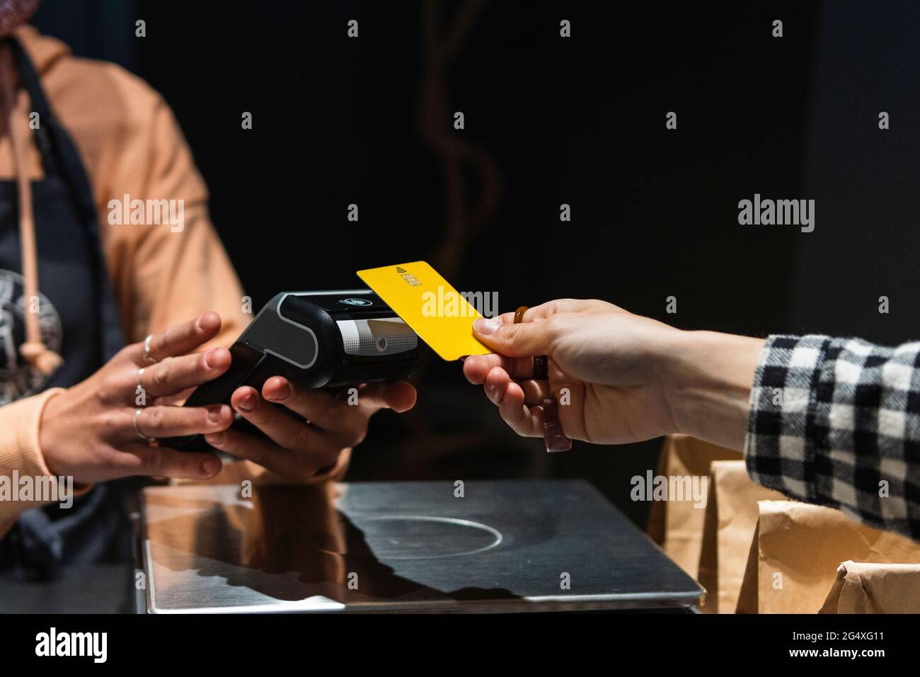 Cliente femminile che dà la carta di credito al proprietario al supermercato Foto Stock