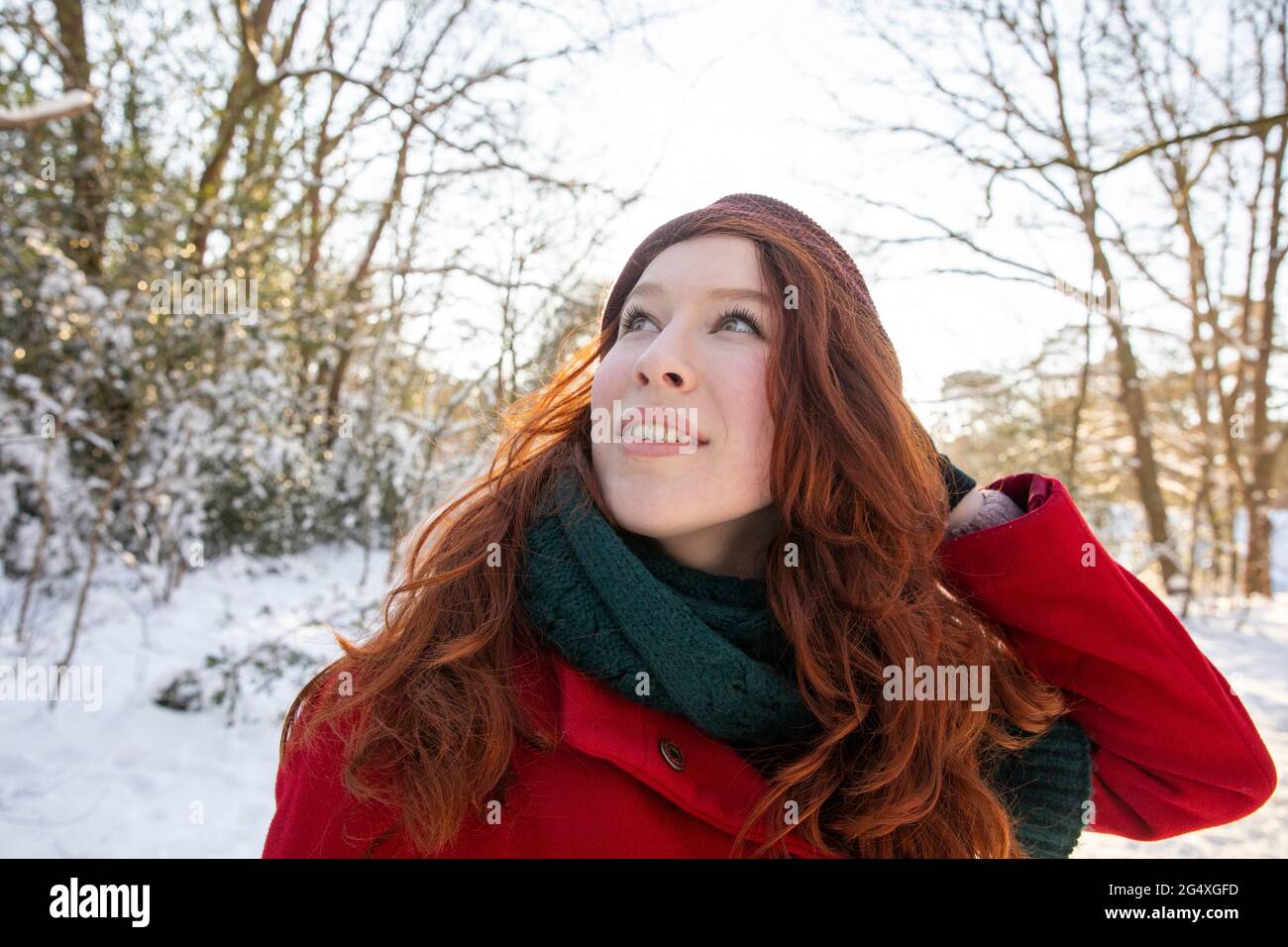 Donna rossa che guarda in su mentre godendo l'inverno Foto Stock