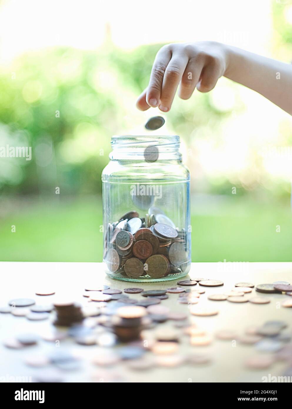 Ragazzo che mette le monete nel vaso di vetro Foto Stock
