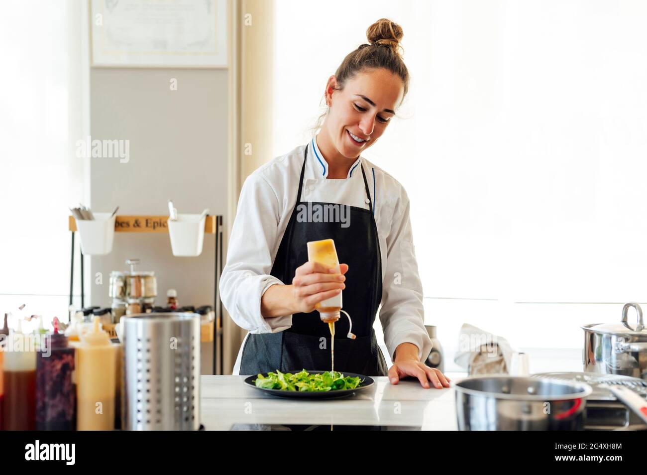 Donna chef versare la salsa di verdure mentre si prepara il cibo nel ristorante Foto Stock