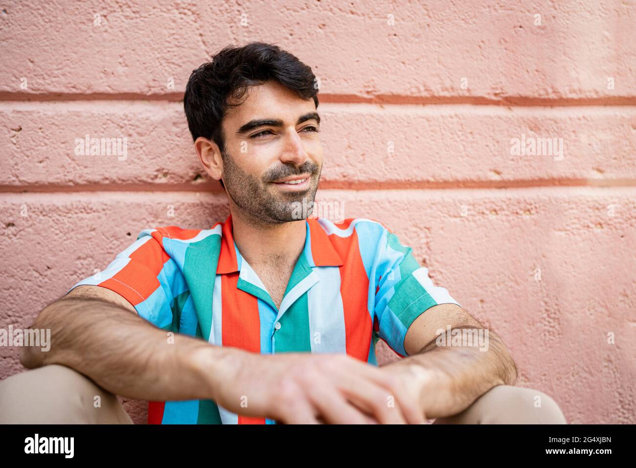 Sorridente bel giorno dell'uomo sognando di fronte al muro di pesca Foto Stock