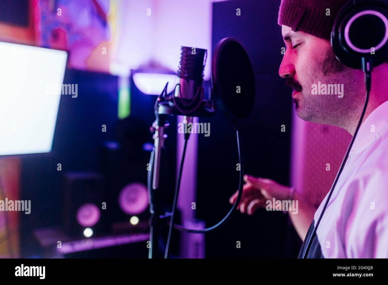 Uomo con gli occhi chiuso gesturing mentre cantava in casa studio Foto Stock