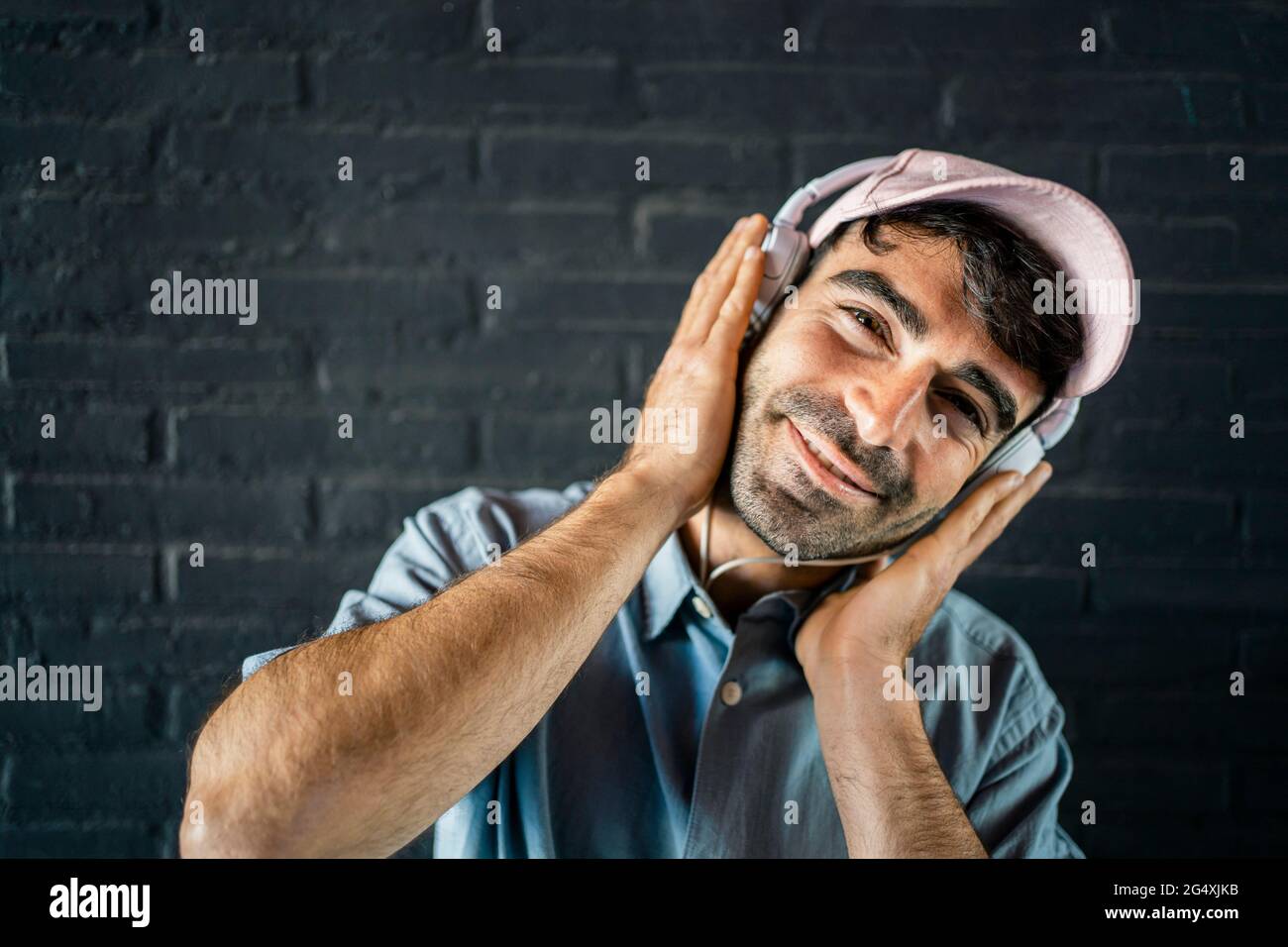 Un giovane sorridente che indossa le cuffie davanti alla parete Foto Stock