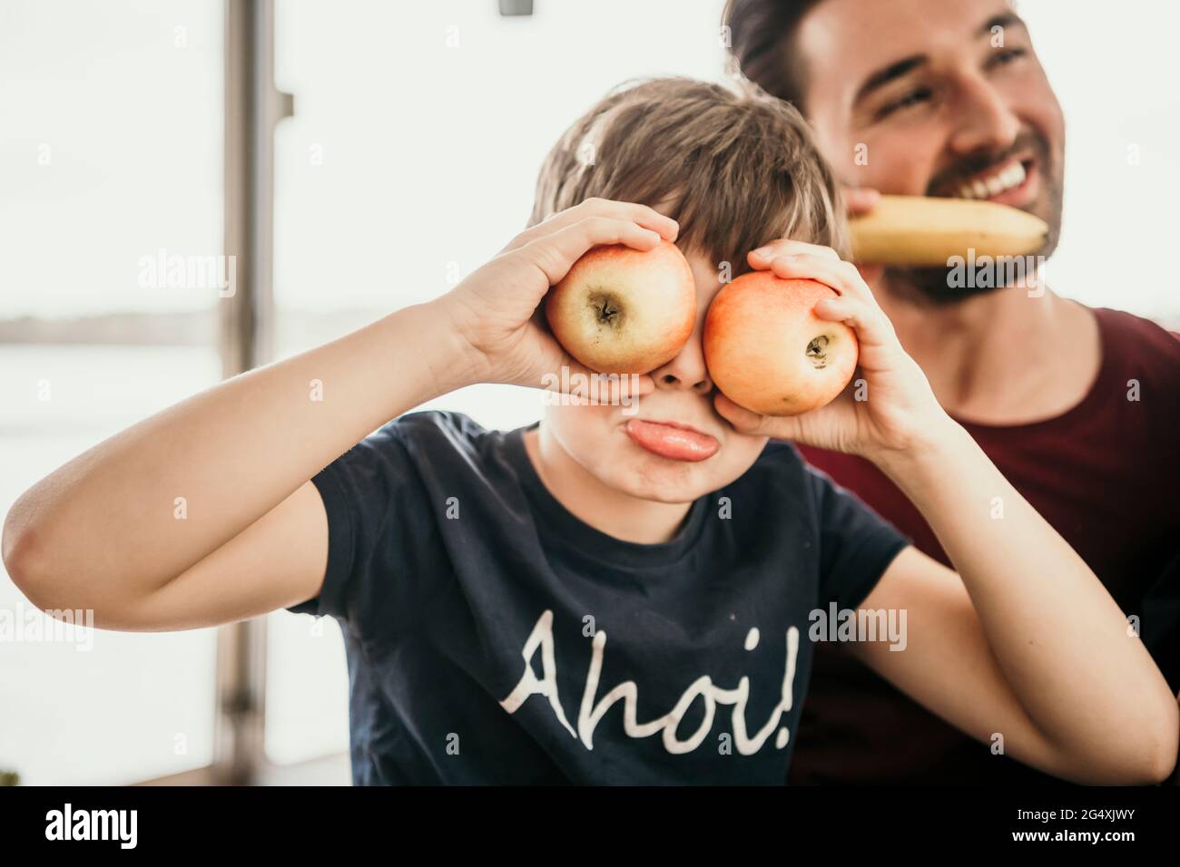 Ragazzo giocoso che copre gli occhi con le mele Foto Stock