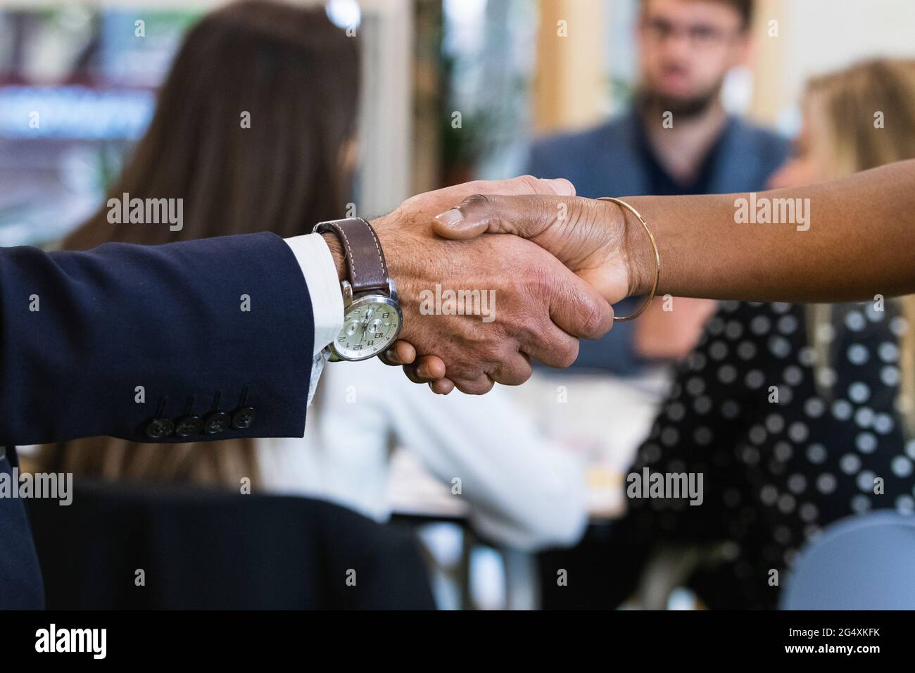 Professionisti maschili e femminili che fanno stretta di mano con i colleghi in riunione all'ufficio Foto Stock