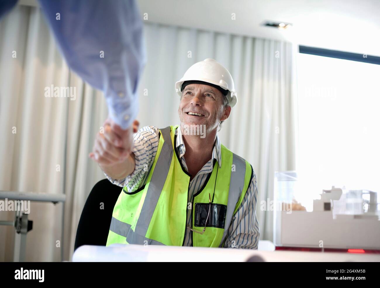 Uomo in abiti riflettenti che fa stretta di mano con il collega in ufficio Foto Stock