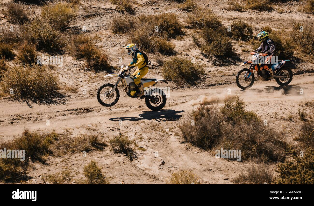 Motociclisti maschi che corrono con moto su strada desertica Foto Stock