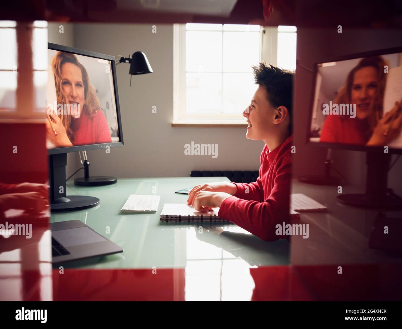 Sorridente ragazzo imparando durante la videochiamata a casa Foto Stock