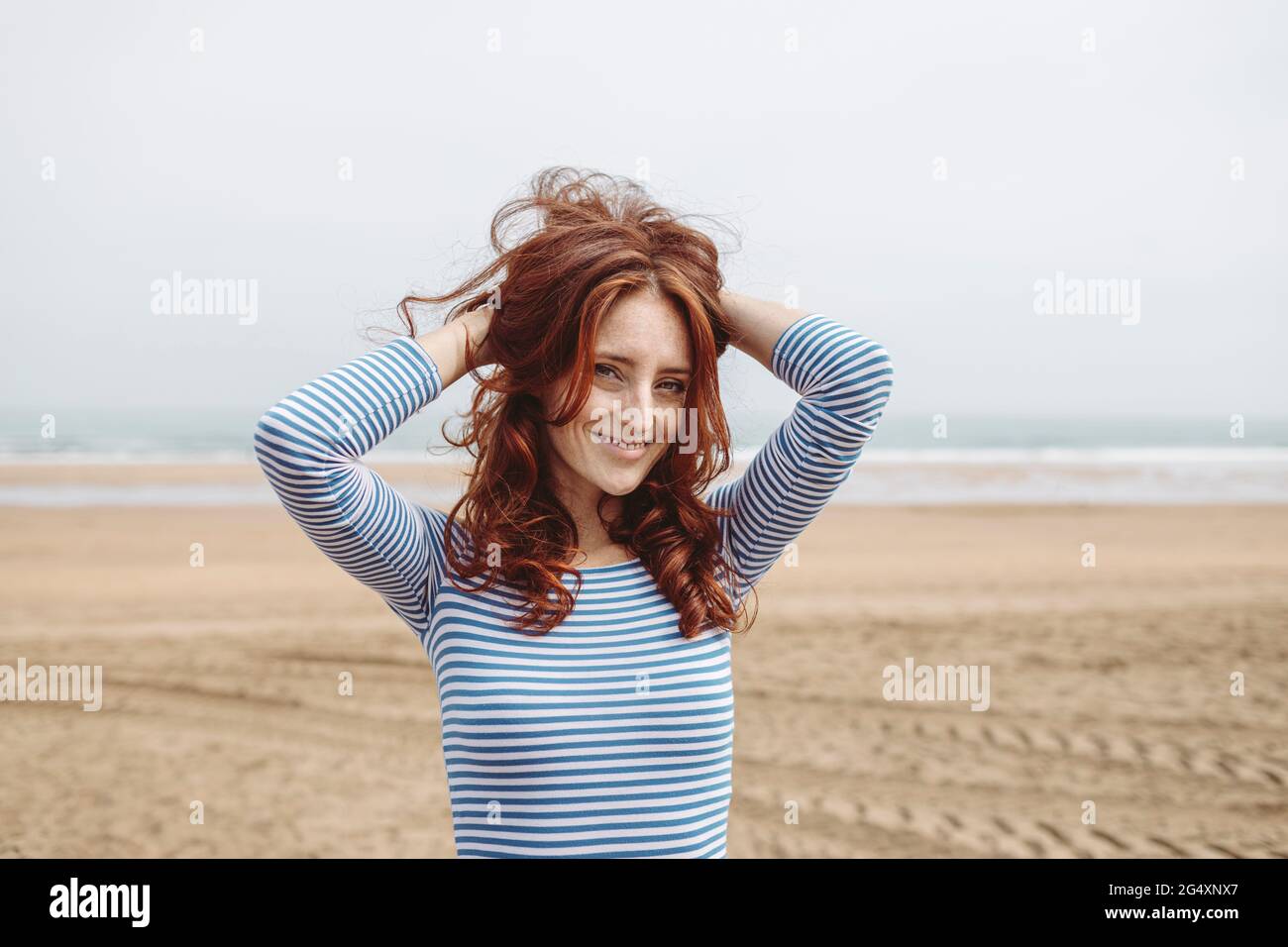 Bella donna con testa in mano in piedi sulla spiaggia Foto Stock