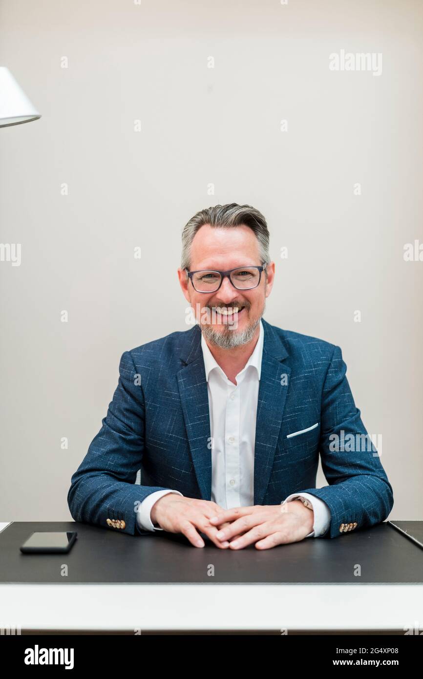 Uomo d'affari sorridente che indossa occhiali seduti in ufficio Foto Stock