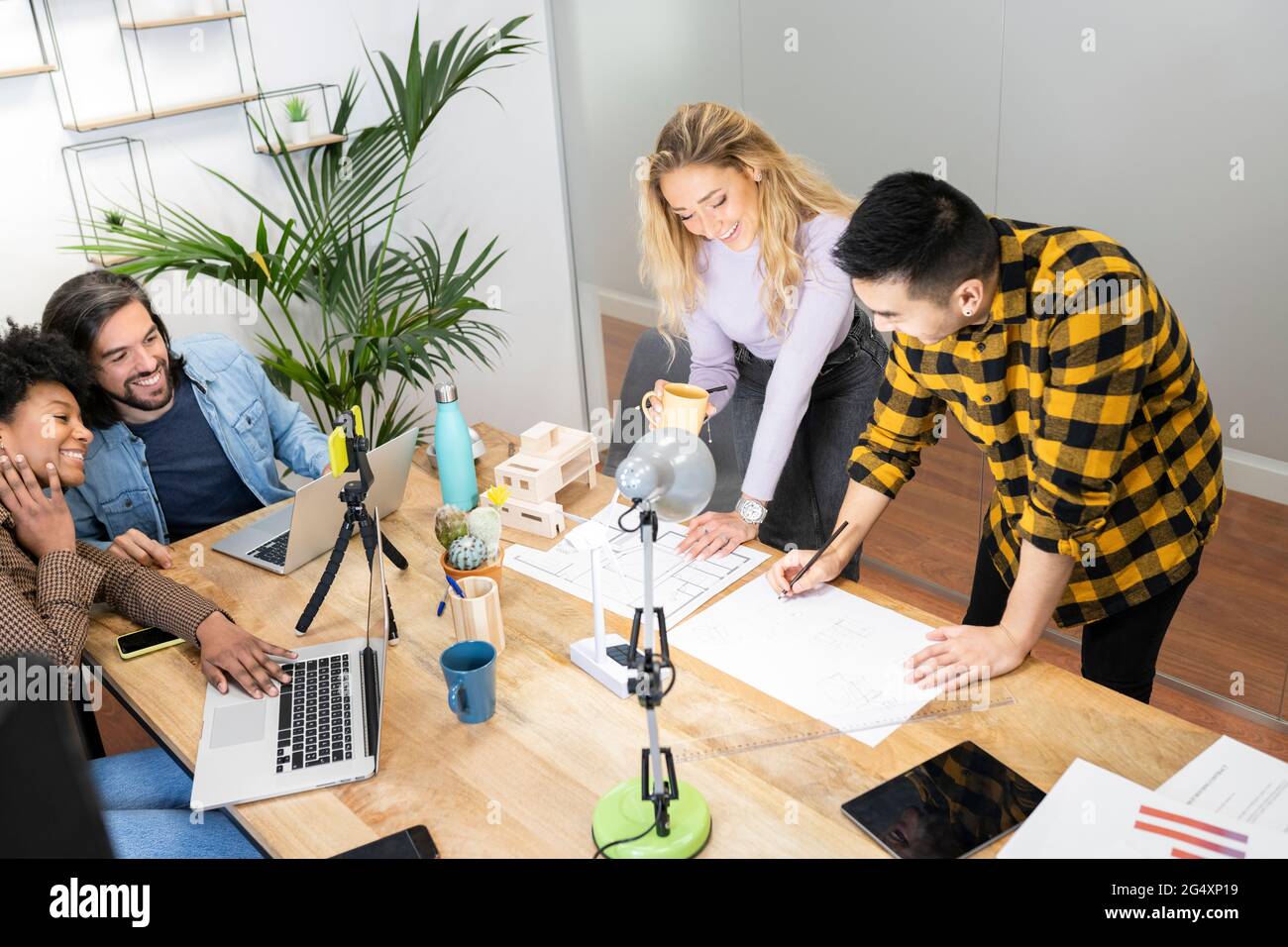 Gli architetti maschili e femminili discutono sulla stampa blu con i colleghi in ufficio Foto Stock