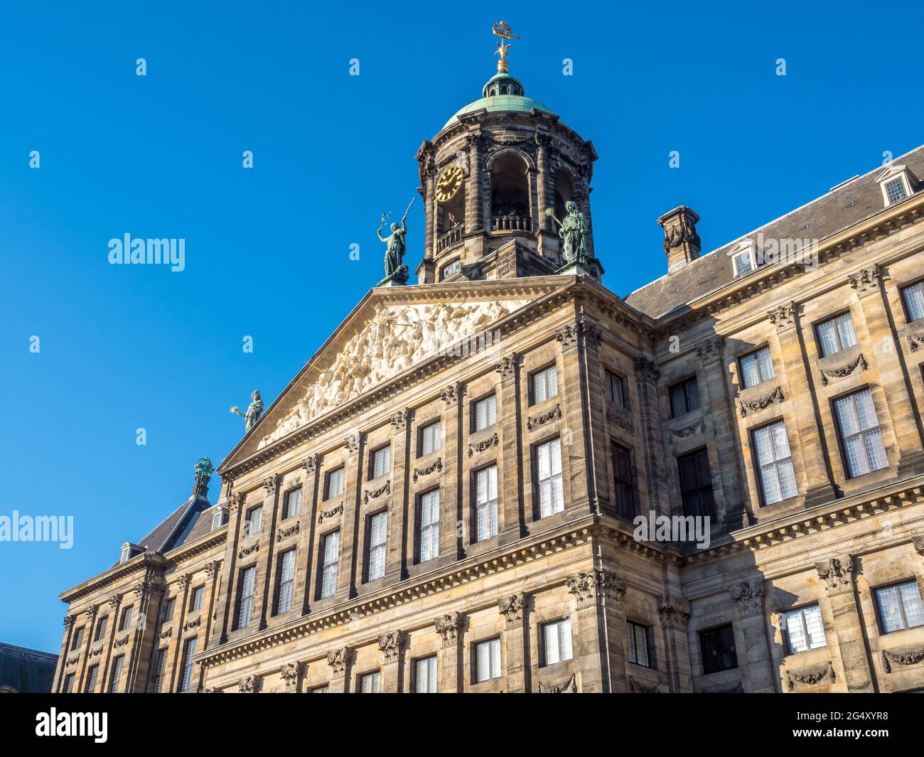 La facciata del Palazzo reale in Piazza Dam, Amsterdam, costruito come municipio durante l'età dell'oro olandese nel XVII secolo, sotto il cielo blu Foto Stock