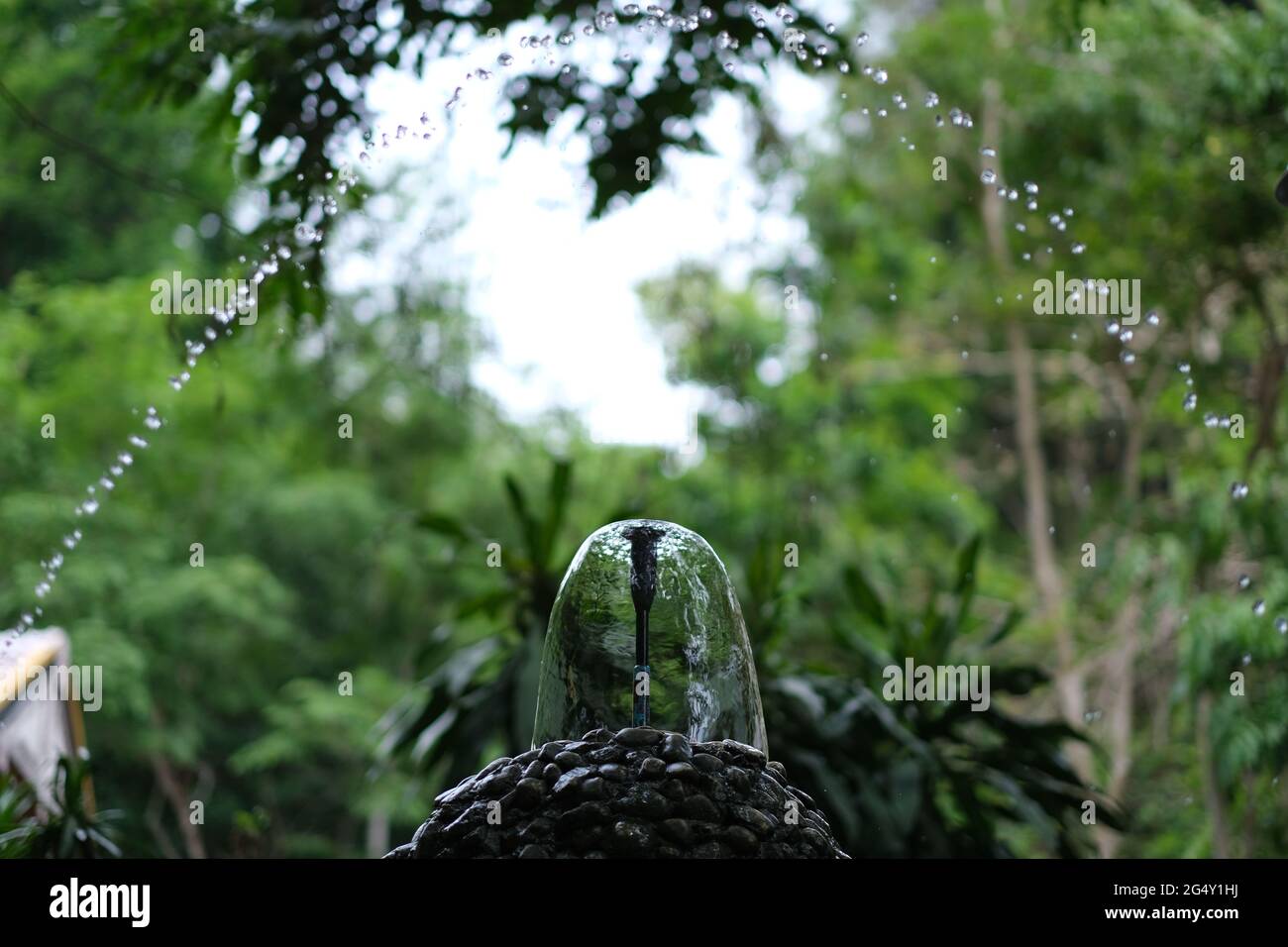 Un insieme di fontane in un giardino del tempio buddista, con gocce volanti e cupola d'acqua Foto Stock