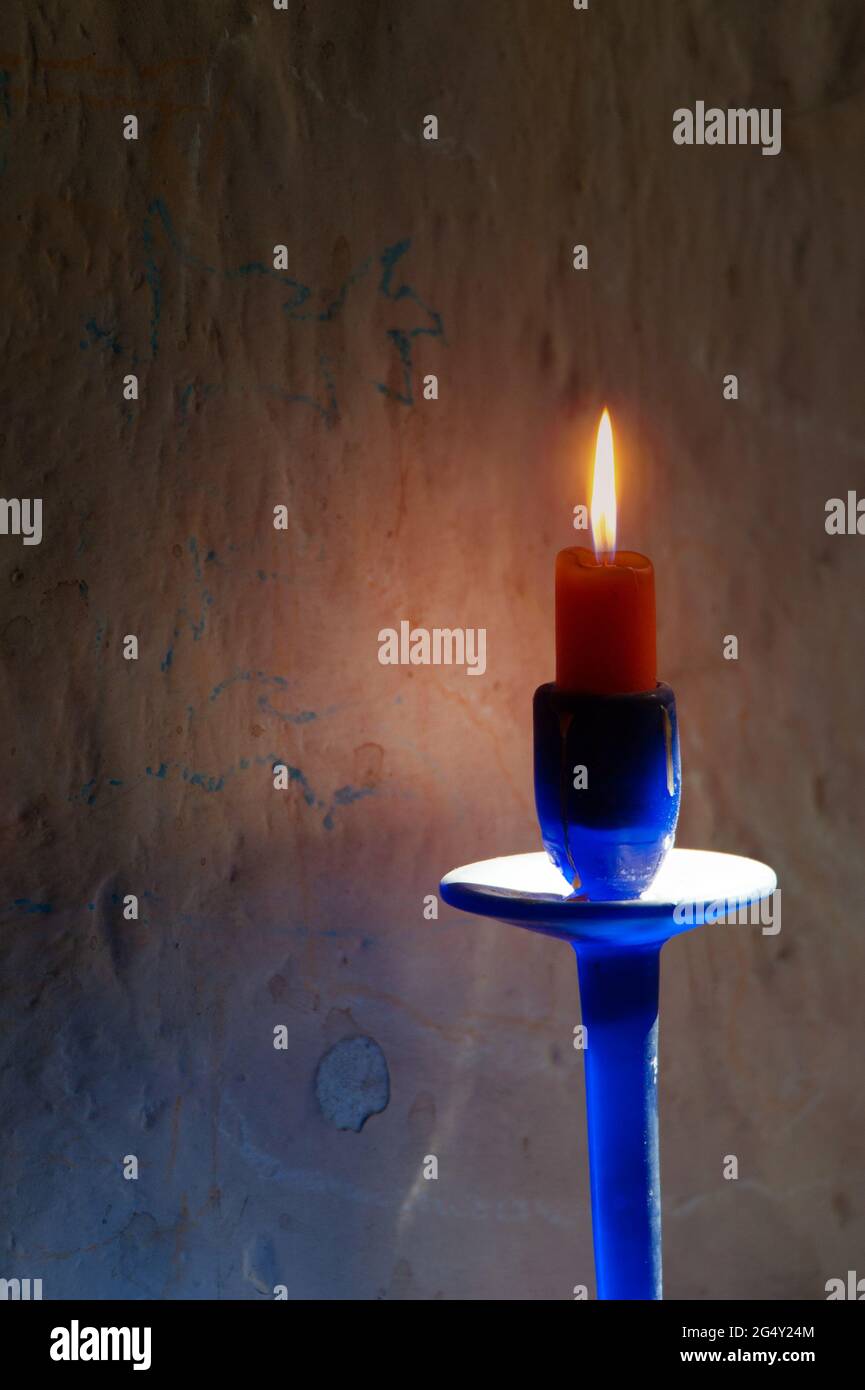Candela rossa accesa in candelabro di vetro blu Foto Stock