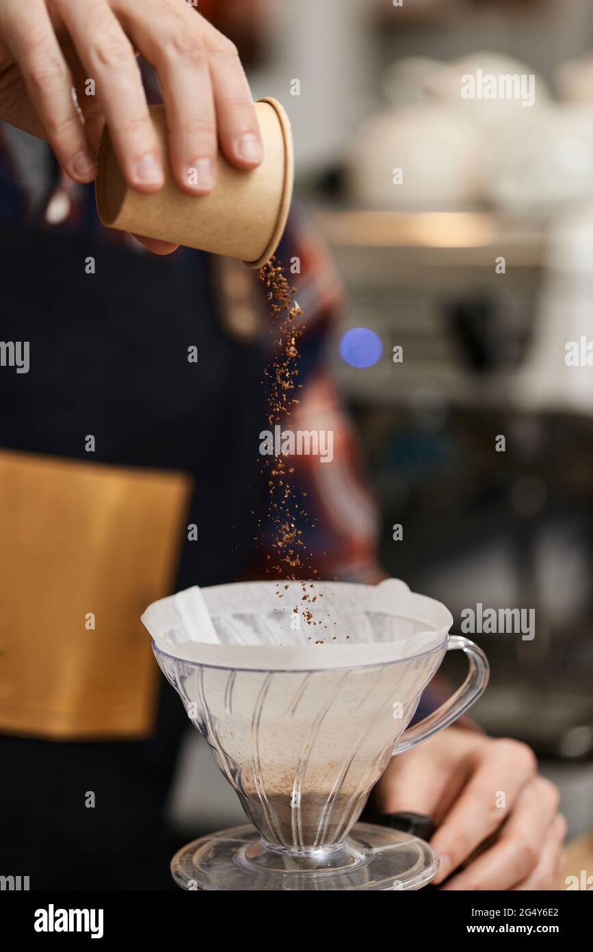 mani maschili che versano caffè messo a terra nel filtro. Foto Stock