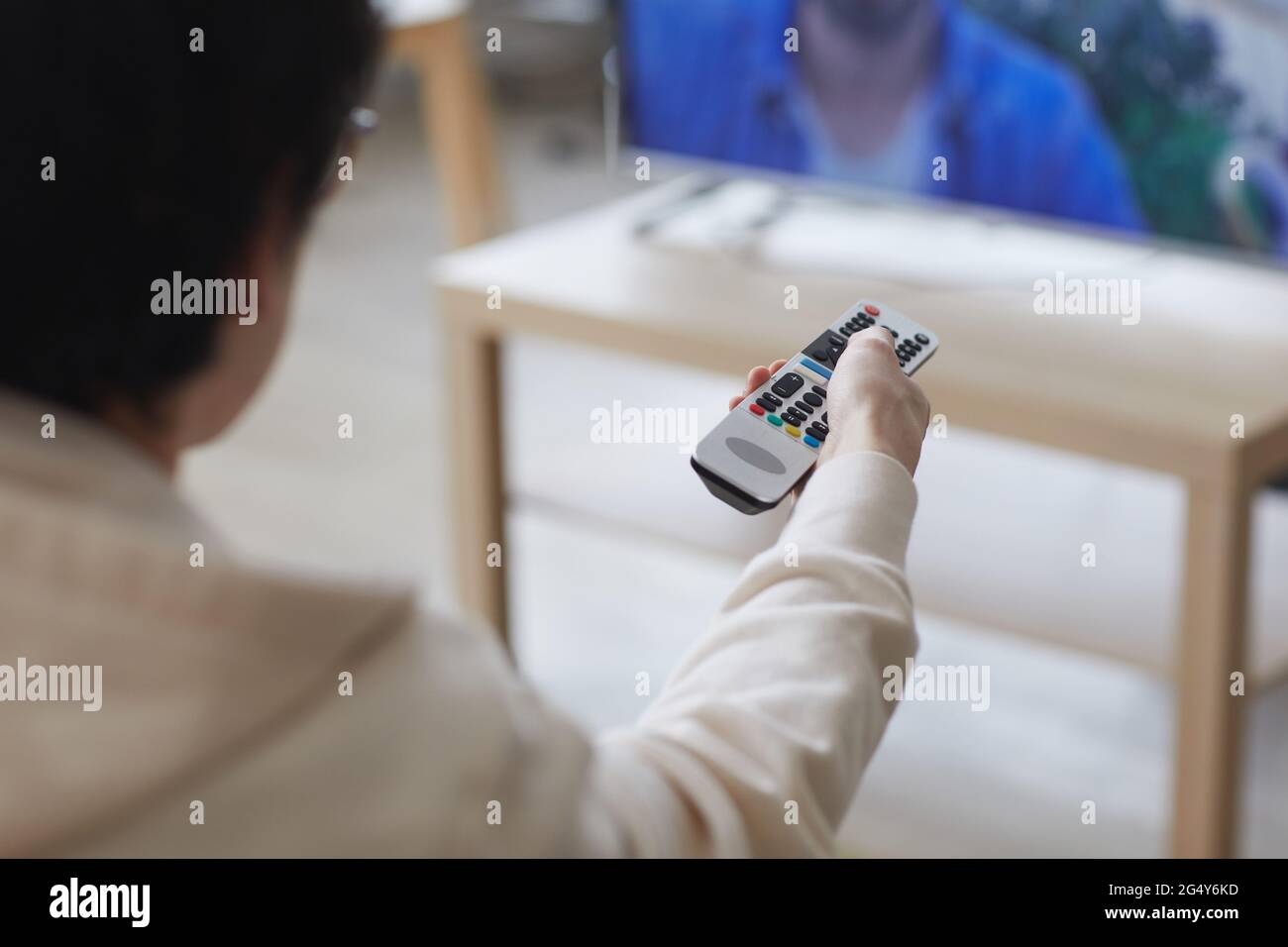 Primo piano tra i giovani che cambiano canale mentre guardano la TV a casa, concentratevi sul telecomando, sul copy space Foto Stock