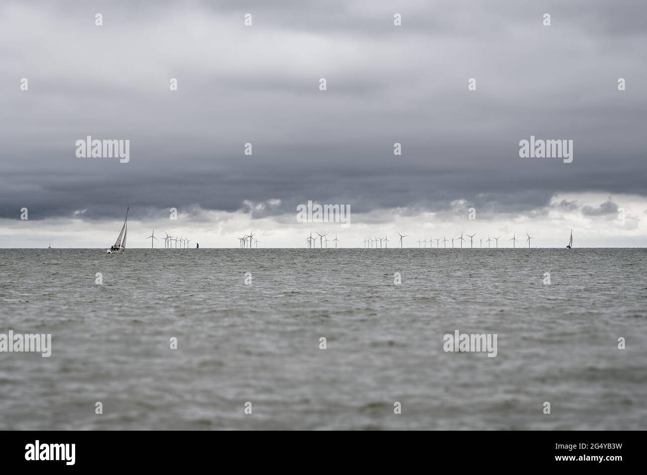 La potenza del vento: Barche a vela e turbine eoliche che sfruttano il vento presso la centrale eolica di Kentish Flats, situata nell'estuario del Tamigi, Kent, Inghilterra. Foto Stock
