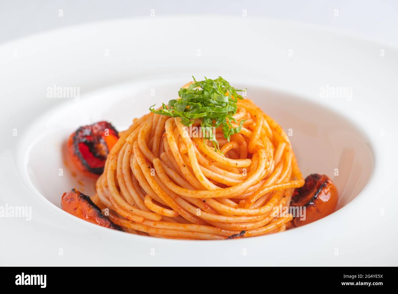 Ciotola di Spaghetti con pomodori ciliegini e basilico grattugiato Foto Stock