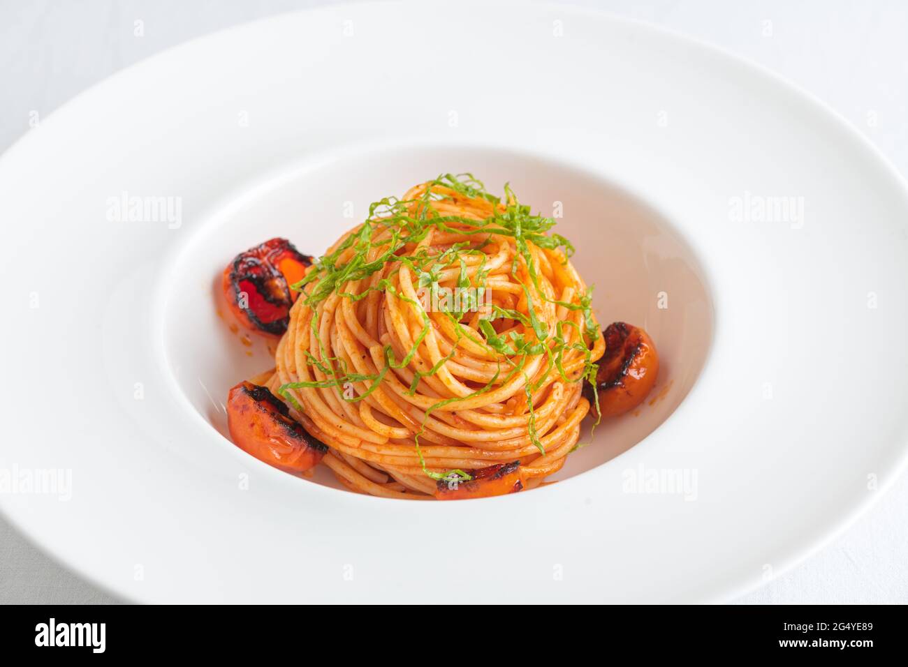 Ciotola di Spaghetti con pomodori ciliegini e basilico grattugiato Foto Stock