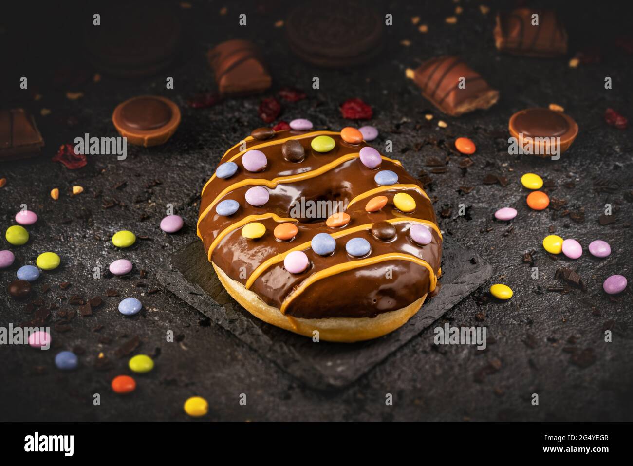 Concetto di cibo dolce veloce, ciambella smaltata al cioccolato dolce decorata con caramelle firecracker Foto Stock