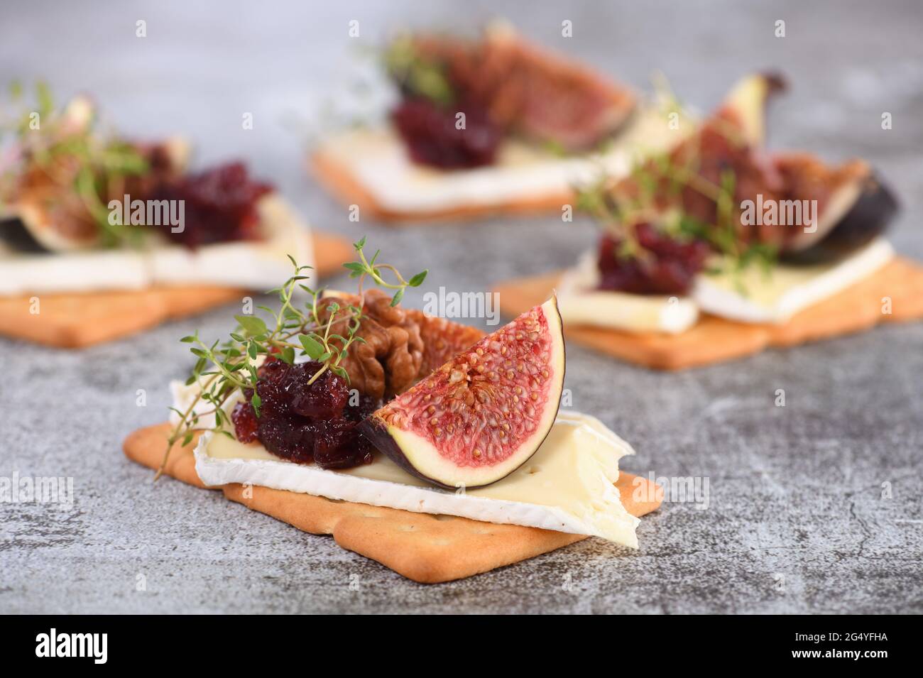 Cracker con una fetta di camembert, marmellata, fichi e noci. Un'ottima idea di spuntino per una vacanza, un picnic o una festa. Foto Stock