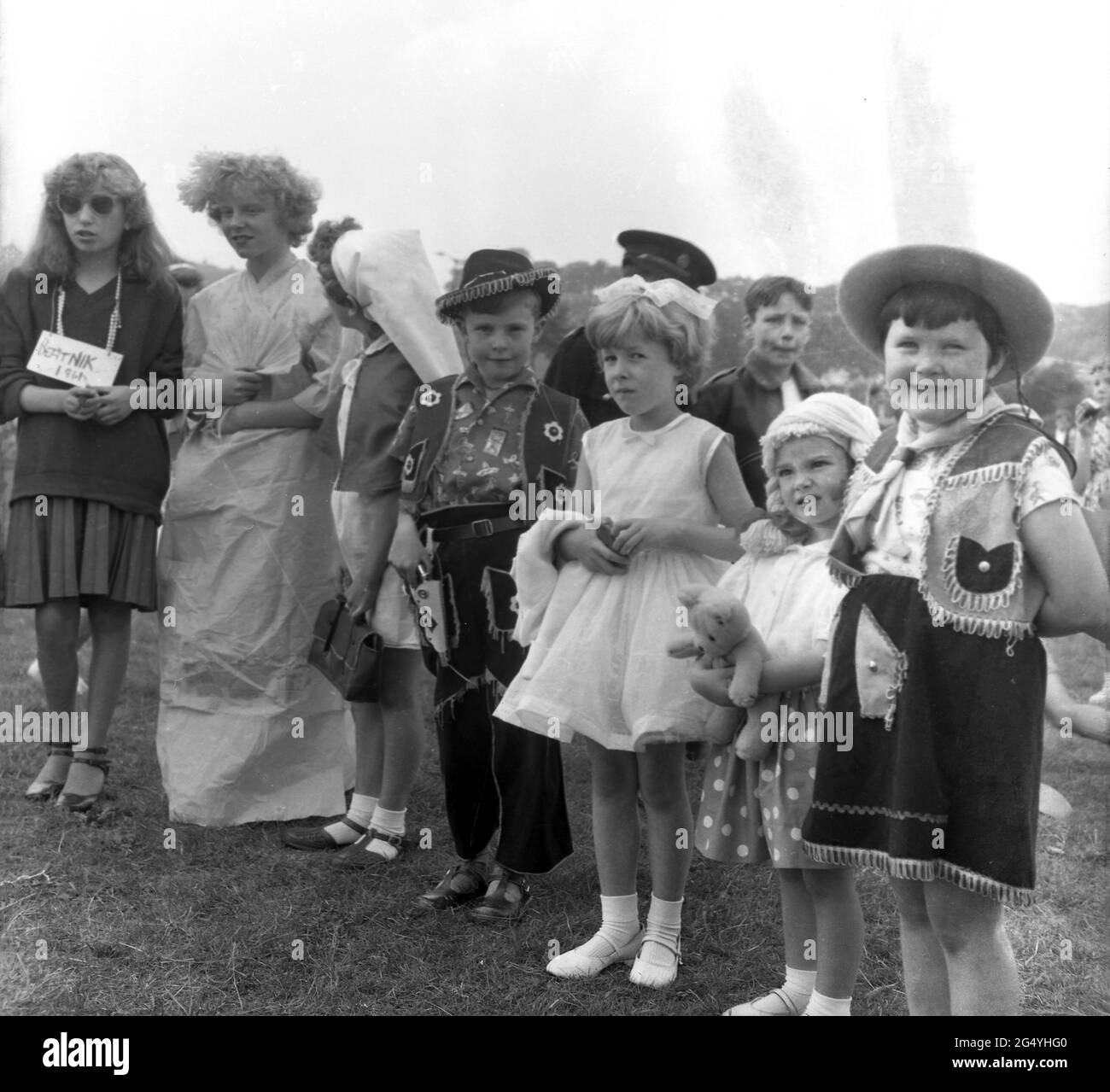 1961, storici, i bambini in costume per il festival della regina delle rose, Farnworth, Lancashire, Inghilterra, Regno Unito, Una ragazza con una scheda con la parola 'Beatnik' su. A partire dagli anni '1880s, il festival della regina delle rose, tenutosi a giugno, divenne un evento annuale nelle città e nei villaggi della Gran Bretagna, specialmente nel Lancashire, la contea conosciuta come la contea delle rose rosse, dopo le guerre delle rose (1455-87). Il festival della regina delle rose è stato simile al festival del giorno di maggio che ha segnato l'inizio dell'estate. Foto Stock