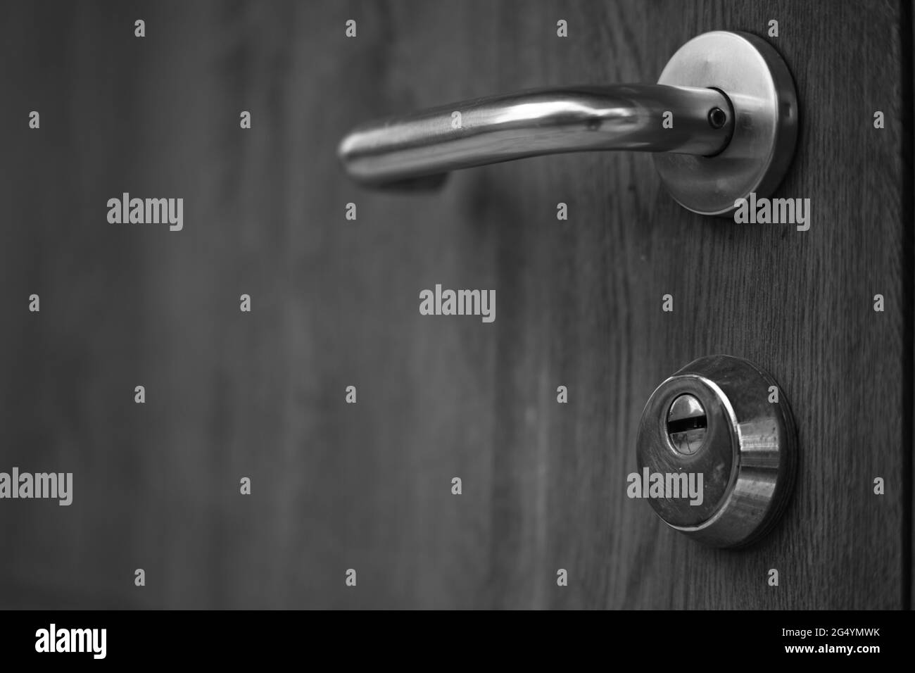 Una porta con maniglia cromata e foro di bloccaggio. Foto in bianco e nero. Foto Stock