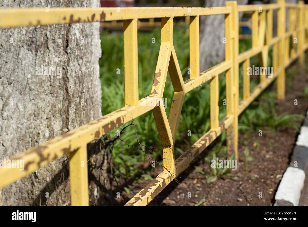 Recinzione gialla con vernice volante. Recinzione aiuole e cortile con una recinzione bassa. Foto Stock