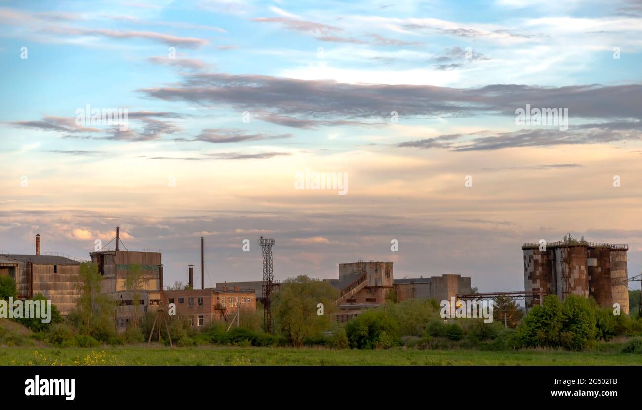 Sullo sfondo del cielo blu e delle nuvole. Impianto industriale. Impianto non funzionante. Al tramonto Foto Stock