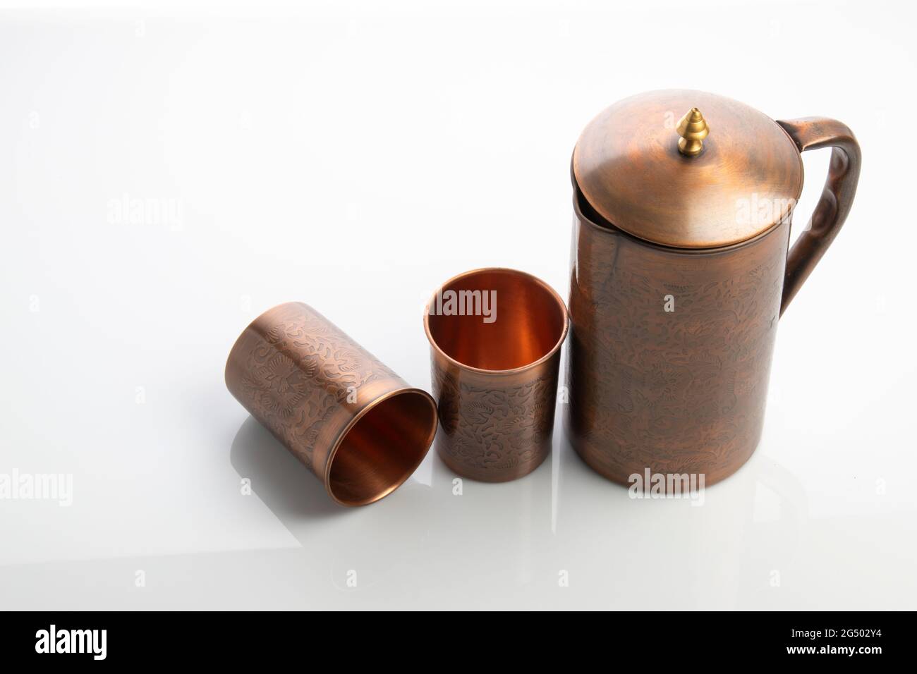 Caraffa e bicchieri in rame antico su sfondo bianco Foto Stock