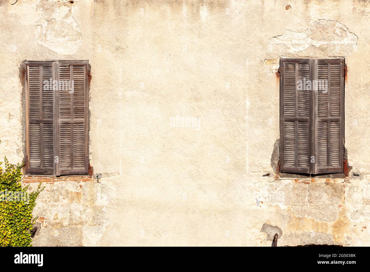 Due finestre con persiane in legno chiuse. Parete gialla. Sartène, Corsica, Francia Foto Stock