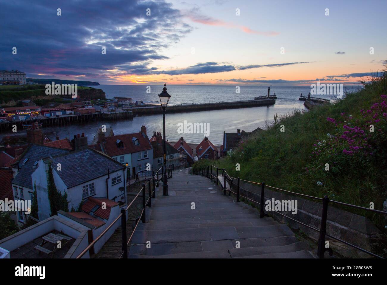 199 scalini che conducono dall'abbazia fino al porto di Whitby. Colori caldi nel cielo al tramonto. Destinazione turistica dello Yorkshire Foto Stock