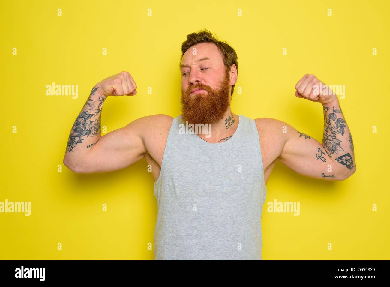 L'uomo con barba e tatuaggi mostra con orgoglio il suo muscolo Foto Stock