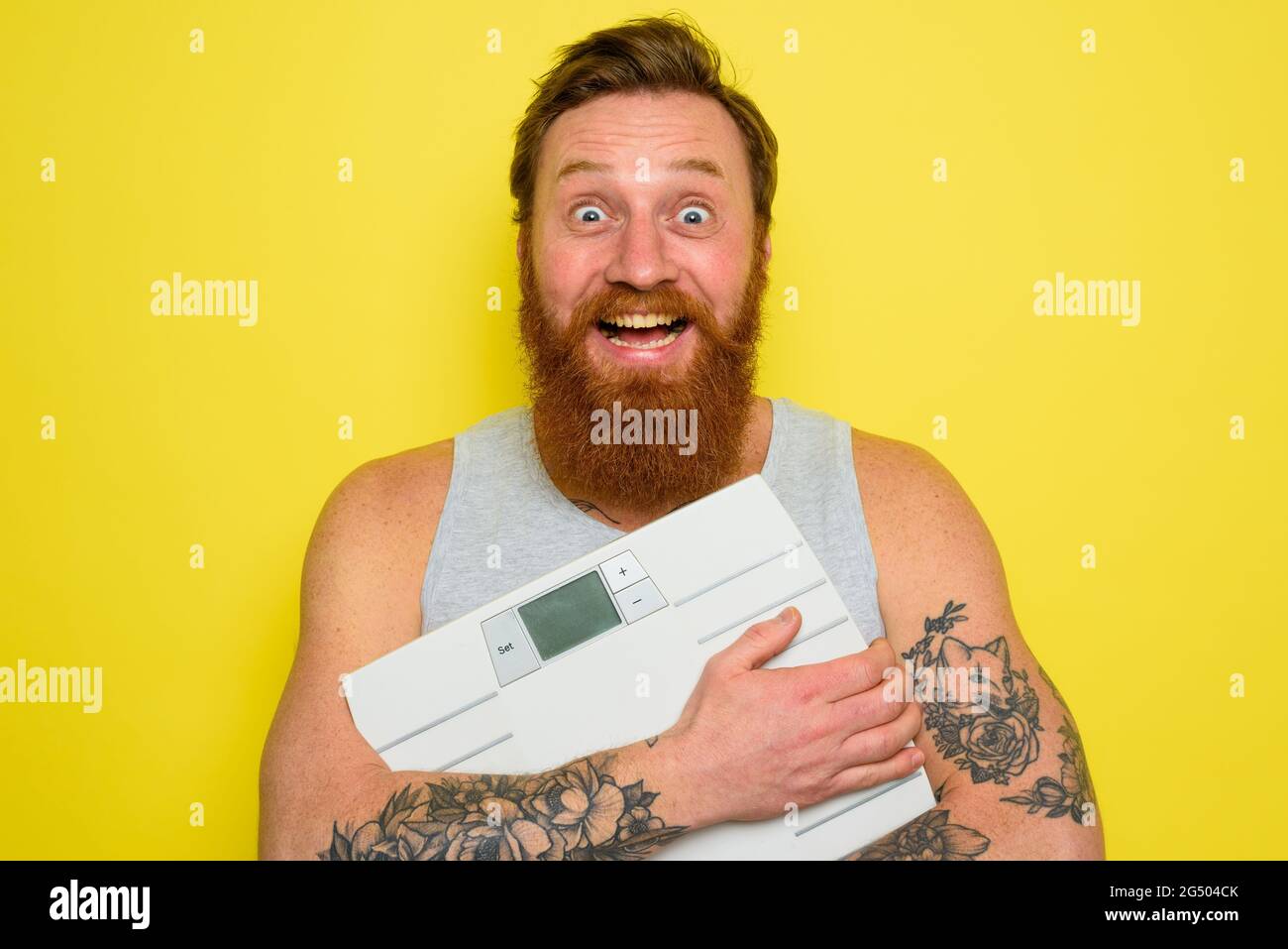 L'uomo felice con la barba e i tatuaggi ha un equilibrio elettronico Foto Stock