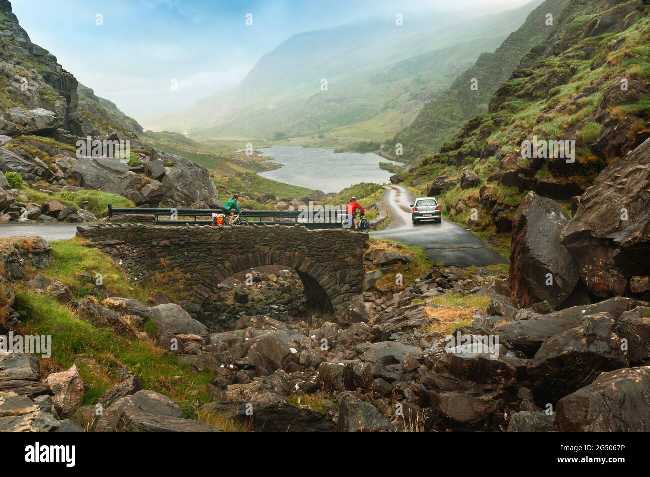 Contea di Kerry, Repubblica d'Irlanda. Eire. Due ciclisti e auto al Gap of Dunloe o Bearna an Choimín. Passo di montagna tra le Reek di Macgillycuddy Foto Stock