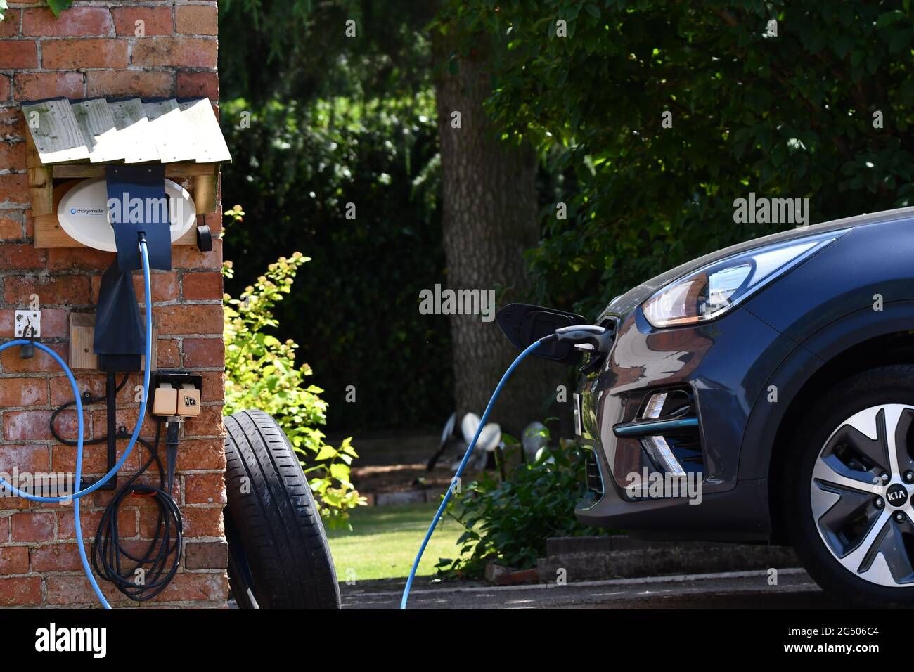 Ricarica di auto elettriche, su vialetto rurale, con un alloggiamento su misura per il caricabatteria per auto. Carica EV. Foto Stock