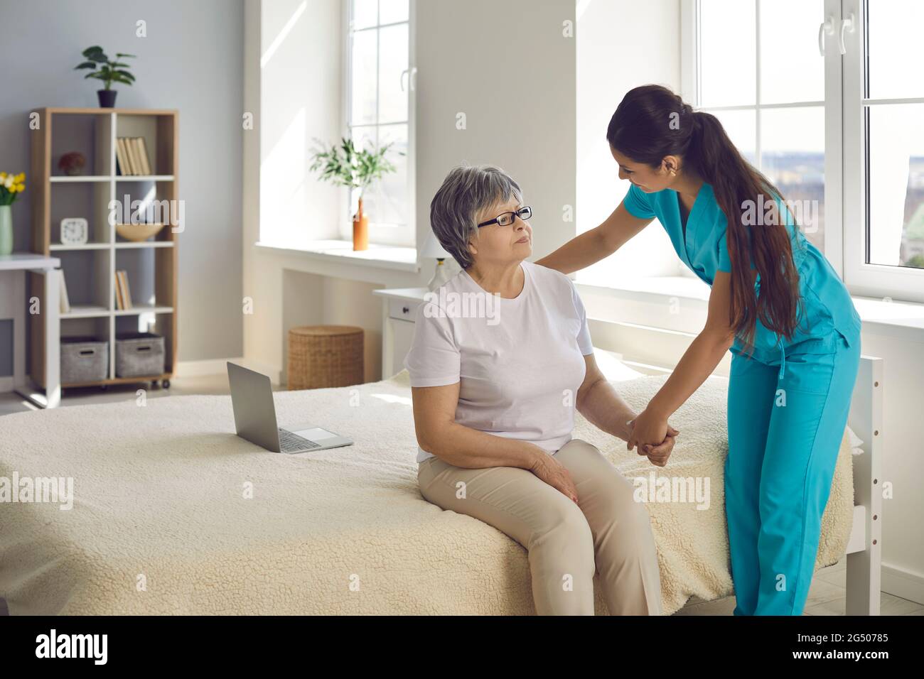 L'infermiera o l'infermiere di assistenza domiciliare sostiene e assiste la donna anziana con tutte le sue esigenze quotidiane Foto Stock