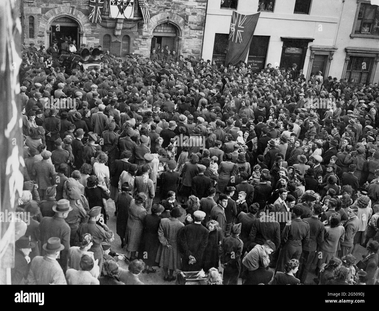 Vittoria in Europa, festa di VE Day a Bodmin, Cornovaglia. Una grande folla si è riunita a Piazza del Monte Folly, Bodmin, l’8 maggio 1945, per ascoltare il discorso del Re che annuncia la fine della guerra con la Germania. La trasmissione radio viene trasmessa attraverso altoparlanti montati sul tetto di un'auto. Foto Stock