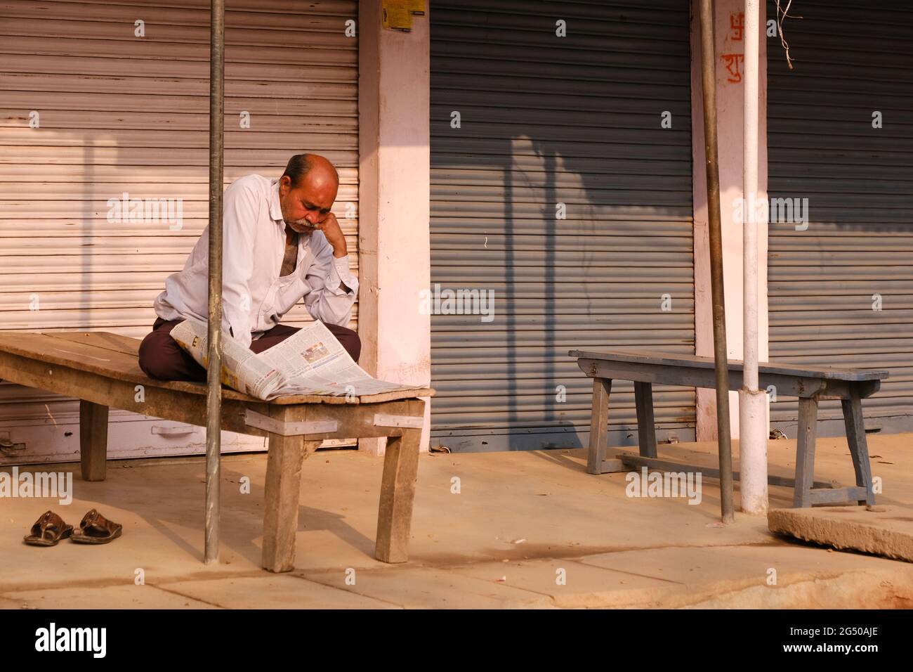 Uttar Pradesh, India, 05 febbraio 2021, un uomo che legge giornale di fronte a negozi vicini. Foto Stock